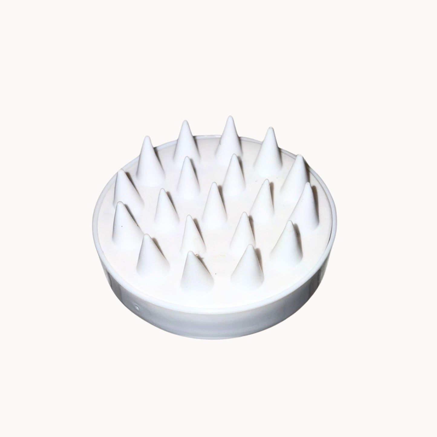 White scalp massager with pointed bristles on a white background