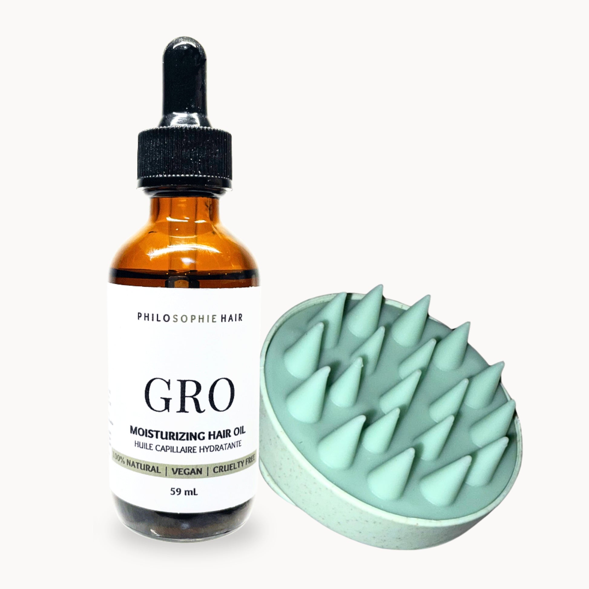 Bottle of Philosophie Hair Gro Moisturizing Hair Oil and a green scalp massager on a white background