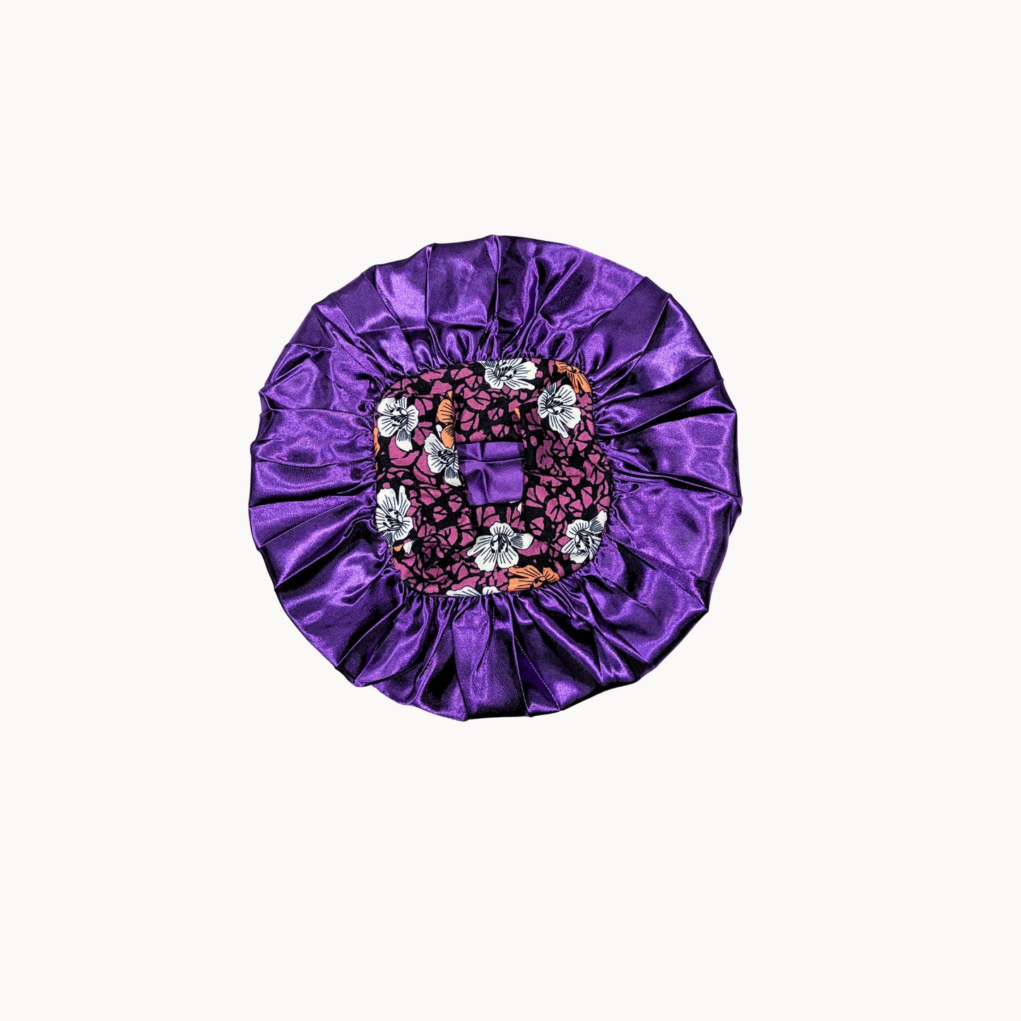 Purple satin bonnet with floral and  details on a white background